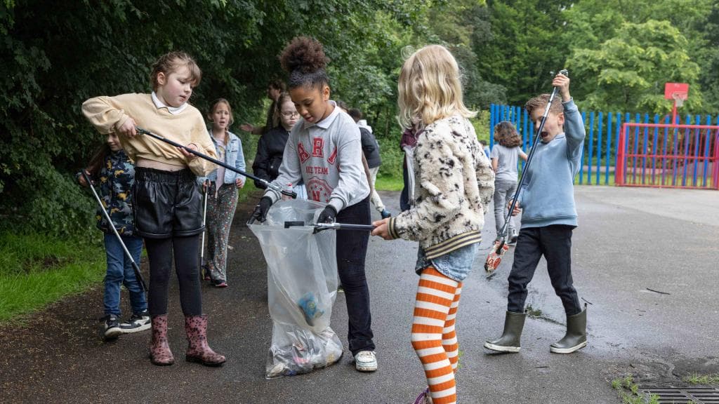 Kinderen prikken spullen van de grond en ruimen afval op
