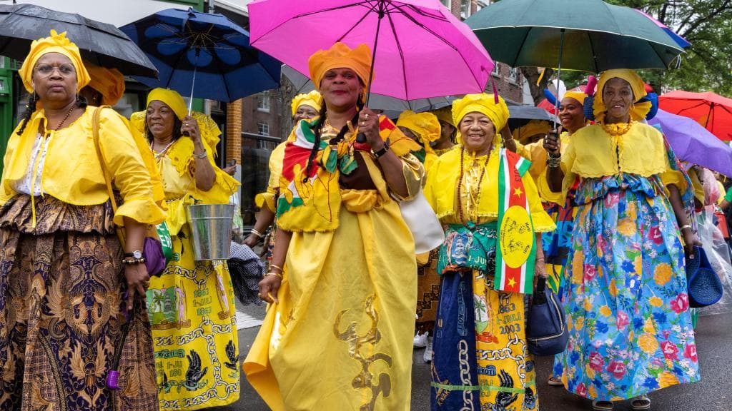 Vrouwen in Surinaamse klederdracht met paraplu's tijdens Keti Koti
