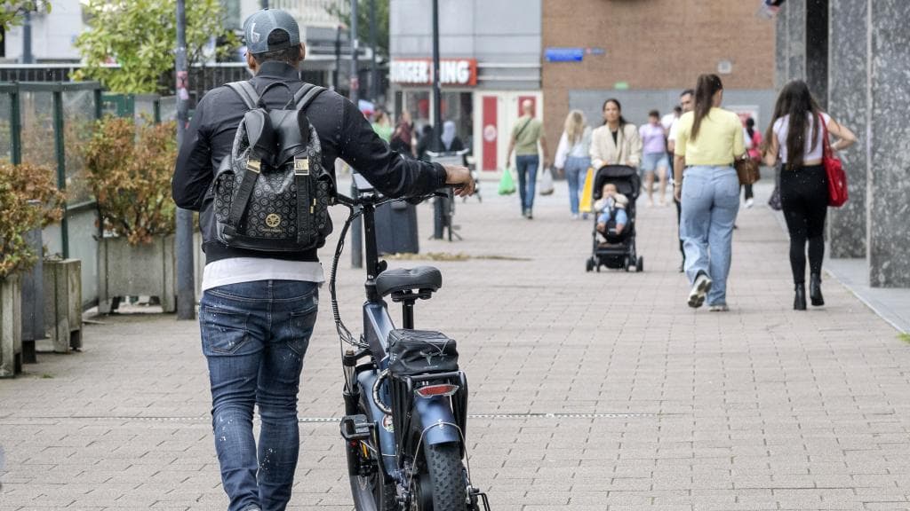 Een man loopt op de stoep met een fatbike aan de hand